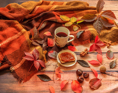 秋天的组成秋天的叶子杯茶和木制背景上的一条温暖的围巾合上了