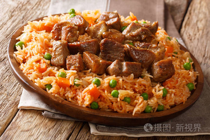 墨西哥传统食品用西红柿青豆和胡萝卜煮熟的米饭在桌子上放上油炸猪肉特写。 水平