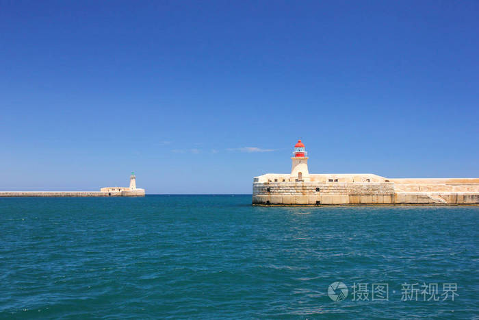 在马耳他瓦莱塔的大港口的两个灯塔在平静深蓝色海