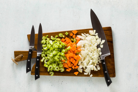 木切割板上的一套刀和切碎的蔬菜