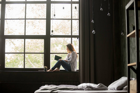 知识窗坐在窗台上的书的妇女在家照片