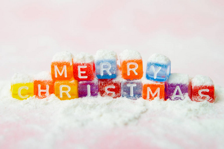 圣诞快乐的词，由五颜六色的字母块在白色的雪背景上。 平躺式顶景假日冬季圣诞节和新年庆祝概念