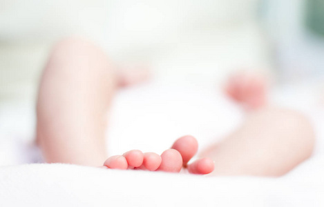 新生婴儿的脚和手指，白色背景失去焦点。