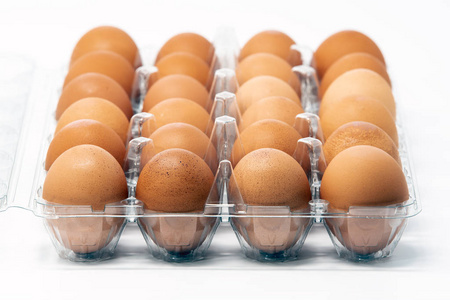 两打棕色有机笼游离鸡蛋在一个塑料容器隔离在白色背景。