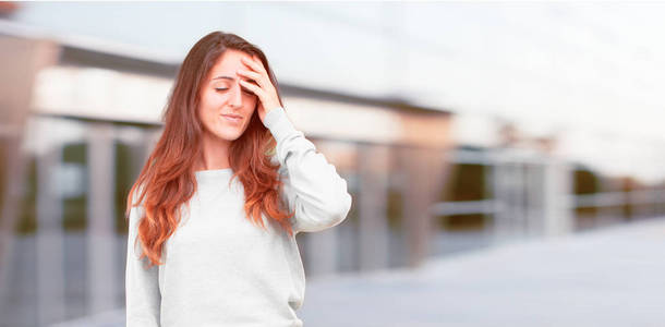 年轻漂亮的女孩全身心地高兴地意识到一些好的和令人惊讶的消息或有一个伟大的想法，微笑着惊讶的表情，同时用手搔头。