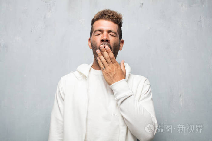 年轻的英俊男子看起来不热情和无聊听着一些无聊和乏味的哈欠在彻底