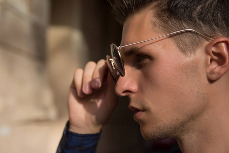 他摘下他的太阳镜男子肖像,在侧面,他持有眼镜接触眼镜,近距离拍摄