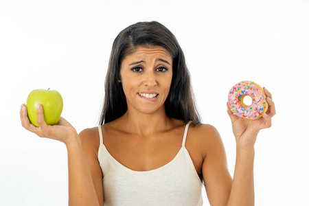 美丽的年轻女性不得不在健康的不健康食品排毒饮食卡路里和饮食观念中选择苹果和甜甜圈。