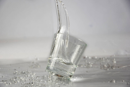 玻璃杯里的水随着溅起的水花和水滴而掉落和跳跃