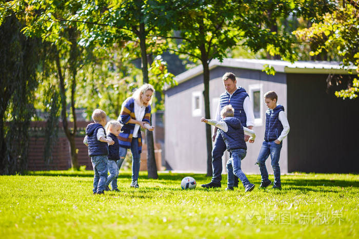 主题家庭户外活动。 一个友好的高加索家庭，六个爸爸妈妈和四个孩子在阳光明媚的日子里，在房子附近的草坪上，带着球跑着。