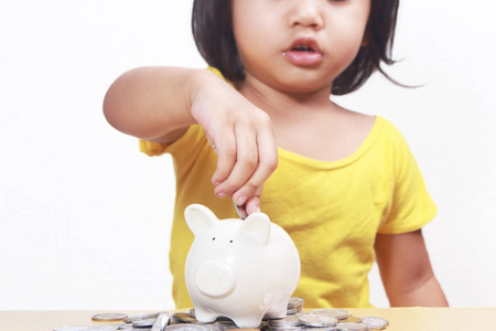 商业经济金融投资理念。 可爱的亚洲小宝贝女儿在储蓄罐里存钱