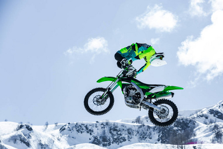 在飞行中的摩托车赛车, 跳跃和起飞的跳板对雪山