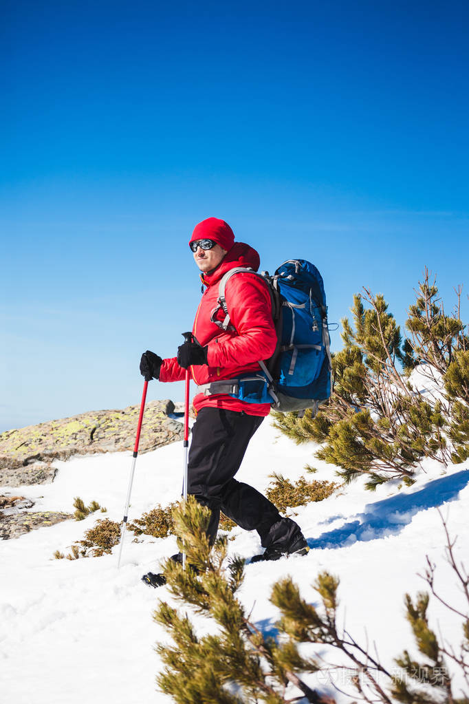 冬天一个拿着登山杖的人上山一个背着背包的登山者在阳光明媚的日子里