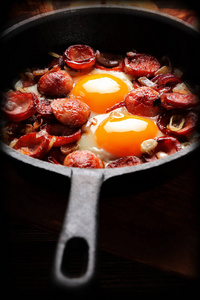 煮熟的鸡蛋和香肠在烤盘上，美味的英式早餐在木制背景