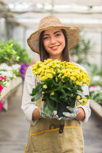 美丽的女园丁在她的花草中照顾植物，在一个温室里工作的亚洲