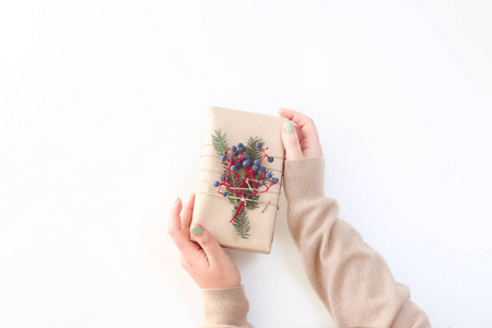 s gift decorated with craft paper and berries in female hands on