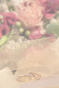 婚礼模糊背景结婚戒指靠近天然玫瑰花束垂直