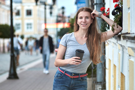 在街上散步时喝咖啡的白人女孩