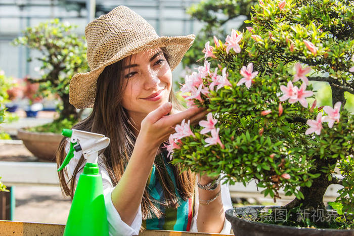 美丽的女园丁在她的花草中照顾植物在一个温室里工作的亚洲
