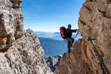 在意大利多洛米斯山脉令人叹为观止的景观中，男性登山者乘坐费拉塔河。旅行冒险概念。