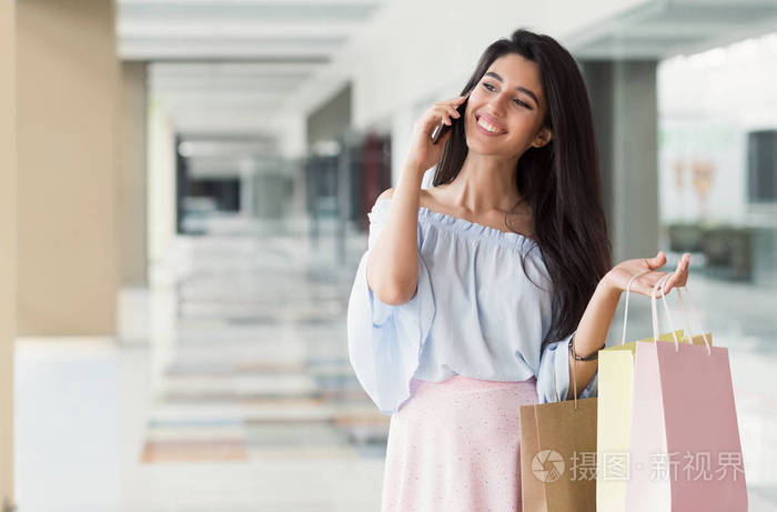 兴奋的女人谈论智能手机和持有纸袋