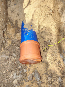 城市便携式水系统HDPE管地下敷设。 。 在沙沟中用橙色棕色工艺覆盖的蓝色塑料管。
