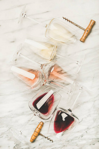 红色玫瑰色和白色的酒杯，以及灰色大理石背景上的开瓶器