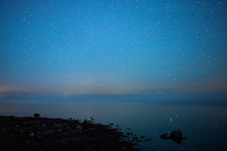 落基湖岸边繁星点点的夜晚。 地平线上的水上雾。