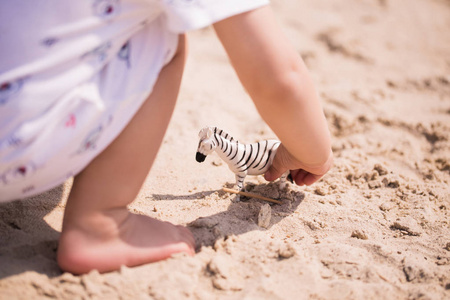 在沙滩上玩耍的小孩手中的玩具斑马