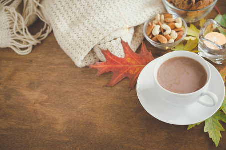 一杯热可可坚果饼干蜡烛和针织格子在乡村木桌上。 惬意的秋天心情温暖的秋天。
