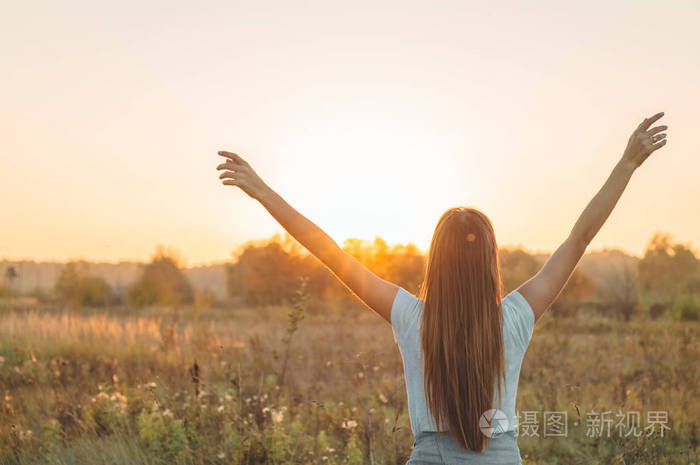 秋天的女孩在田野上享受大自然户外美容女孩在阳光照射下举起双手美丽