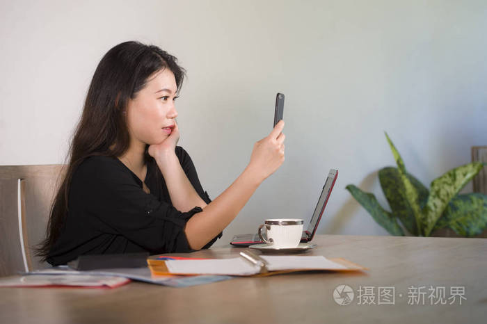 年轻,美丽,快乐的亚洲韩国女商人在公司办公室桌上用手机自拍照片