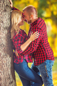 年轻的情侣在秋天公园拥抱和亲吻。