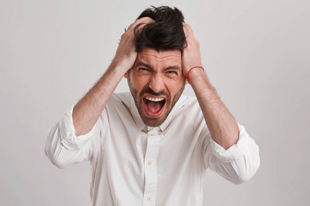 年轻的黑胡子男人因为一些大麻烦看起来尖叫,双手抱着他的头前额和