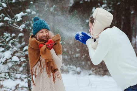 快乐的年轻夫妇在冬天散步，扔雪球，在雪林的户外玩得很开心。 积极的寒假观念。