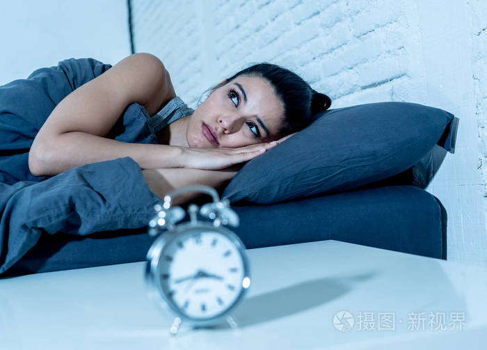 失眠和绝望的美丽拉丁女人晚上醒着不能睡觉看着钟患失眠睡眠障碍的