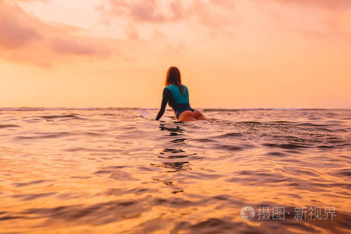 在温暖的夕阳下，冲浪板上漂浮着的冲浪女孩