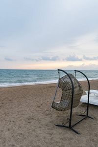 藤条休闲挂椅，白色枕头背景美丽的海滩。