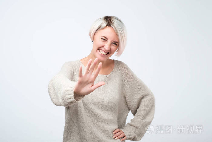 积极的妇女身着灰色毛衣显示停止手势, 要求停止开玩笑, 因为她厌倦了笑