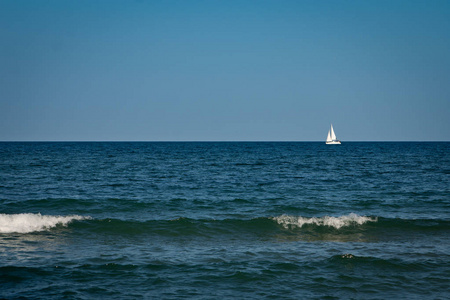 游艇与白色帆走到海里。前景中的波浪
