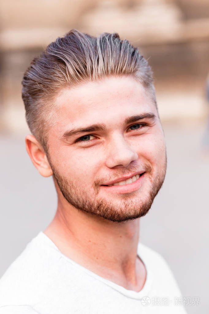 穿t恤的运动金发男孩在一个夜晚城市的背景下