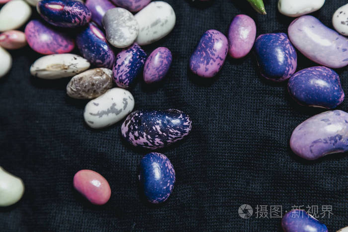 不同颜色的豆子种子躺在深色织物上关闭