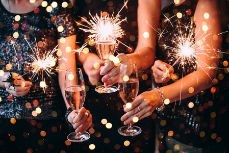 朋友们用孟加拉灯和玫瑰香槟庆祝圣诞节或新年前夜派对。