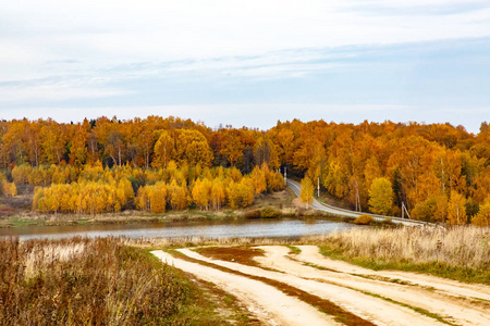 这个村庄在湖上秋天森林的背景上。 俄罗斯的秋天