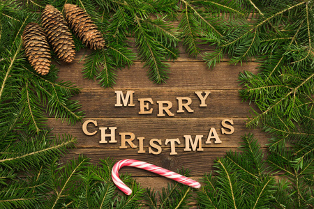 在木制背景上铭刻圣诞快乐。 杉枝棒棒棒糖棒的框架。