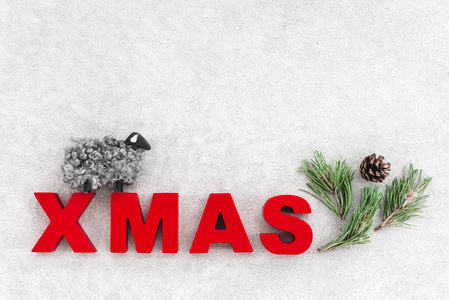 北欧风格的简单圣诞装饰。 小羊松树枝锥和圣诞节这个词在混凝土背景上。