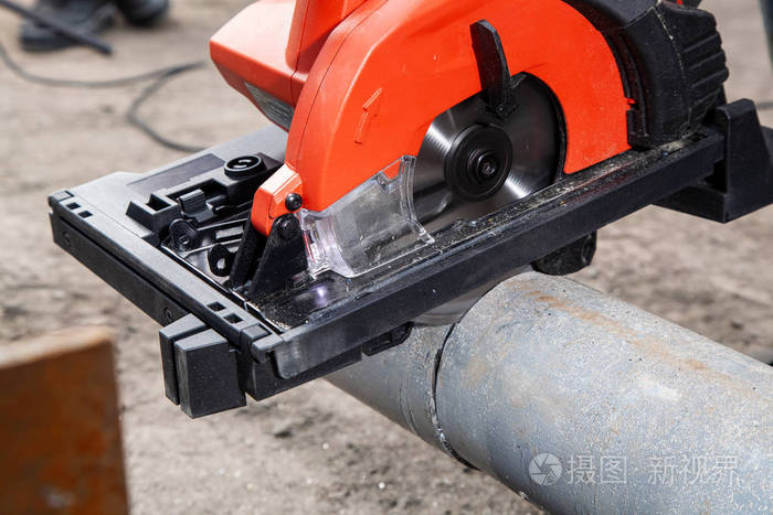 重工工人在车间用角磨机切割钢管.