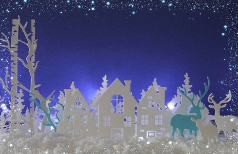 神奇的圣诞纸剪下冬天的背景景观，房子树鹿和雪在白光背景前