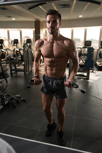 肌肉男在健身房里用电缆在机器上为胸部做重物运动