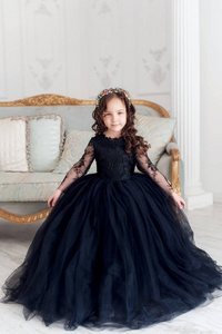 穿着黑色公主蓬松连衣裙可爱微笑的小女孩的肖像。